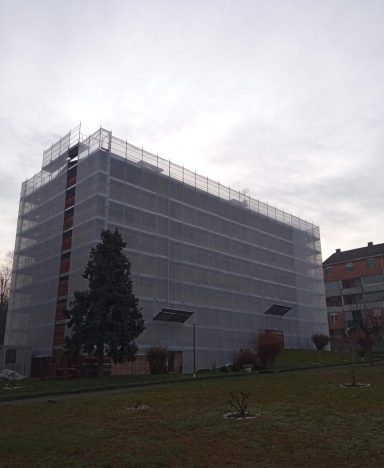 Edificio in ristrutturazione coperto da impalcature con cielo nuvoloso.