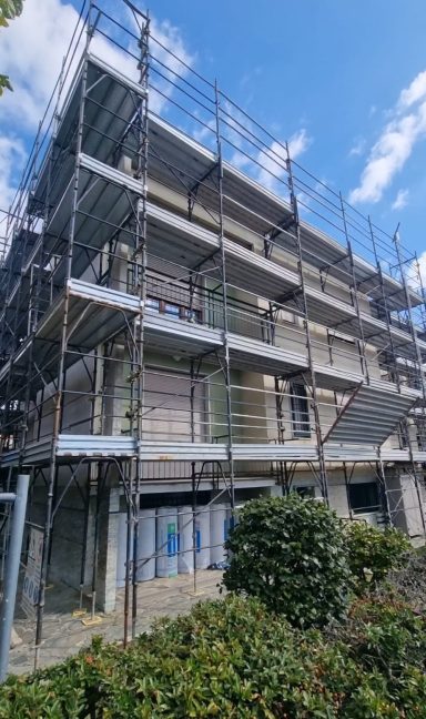 Edificio in costruzione con impalcature e cielo parzialmente nuvoloso.